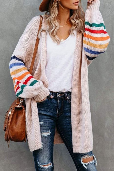 A model wears the long light pink cardigan, highlighting the bold, colorful stripes on its voluminous sleeves.