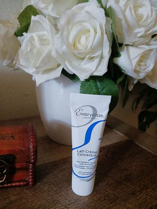 A tube of cream placed elegantly in front of white roses.