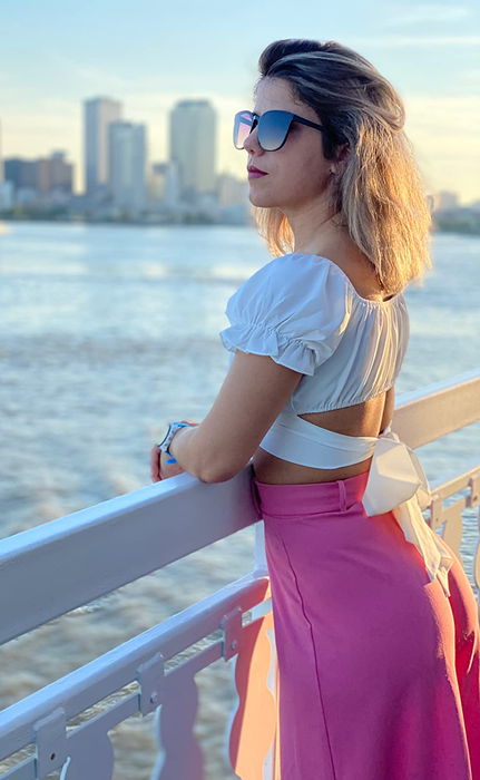 Reviewer demonstrating the tie-back feature of the white top, paired with a pink skirt.