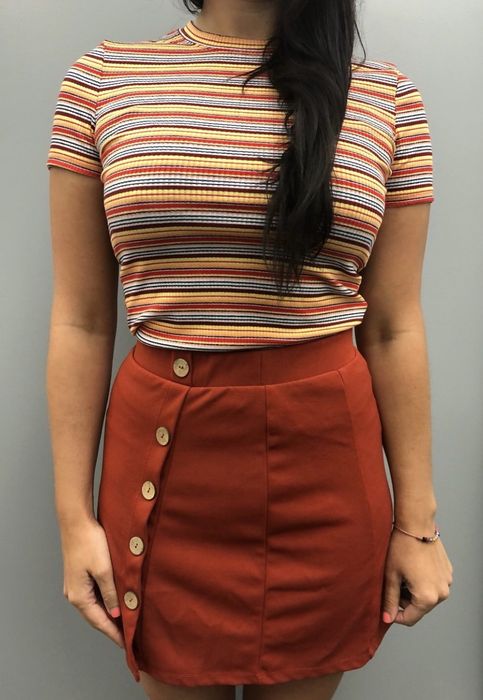 A reviewer rocking a tight multicolor striped t-shirt with a brown skirt