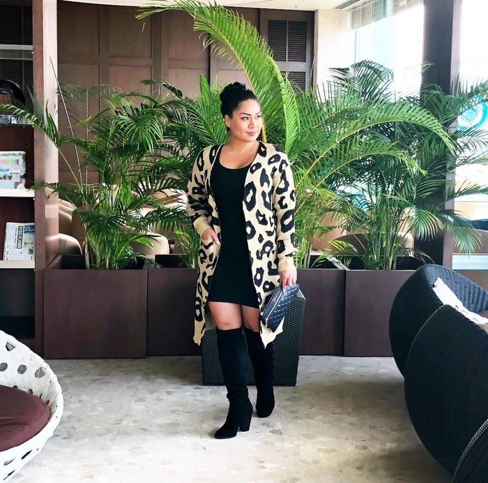 A reviewer showcasing the leopard cardigan paired with a black dress