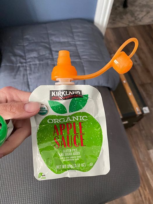 a reviewer demonstrating how to use the lid on an apple sauce pouch