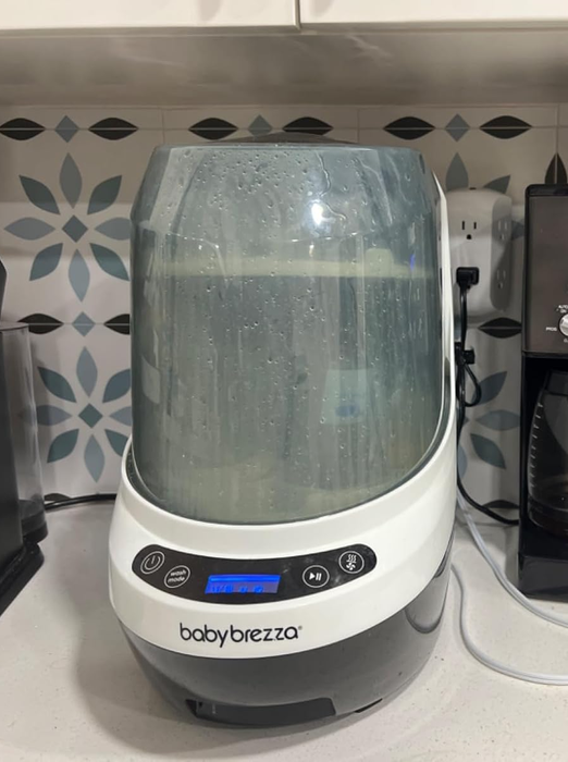 A modern kitchen setup featuring the Baby Brezza Formula Pro and a Cuisinart coffee maker placed side by side, exemplifying convenience and contemporary living.