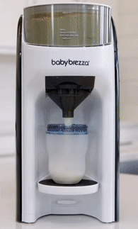 A Baby Formula Maker dispensing formula into a bottle on a kitchen countertop