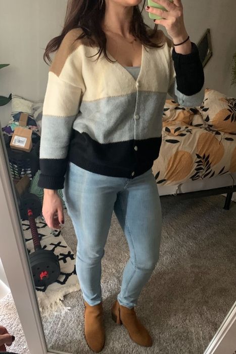 A reviewer styles the sweater in a combination of tan, cream, gray, and black stripes.