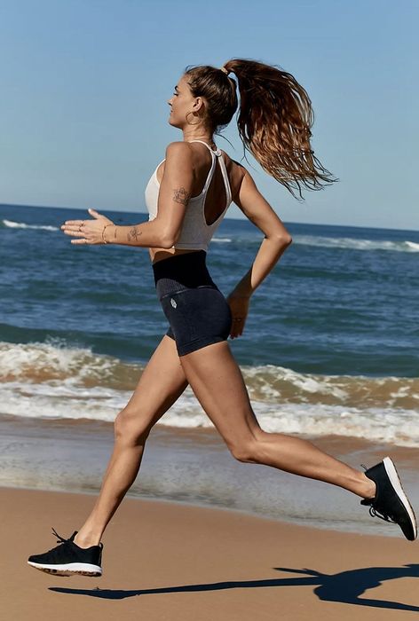 Another model running on the beach in black shorts