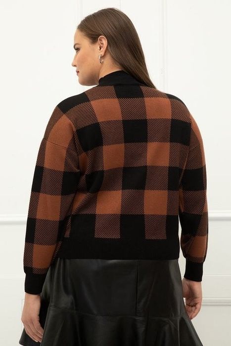 A model showcasing the plaid sweater paired with a leather skirt, viewed from the back.