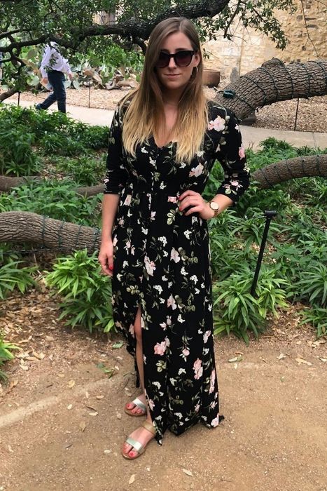 A reviewer showcasing a black floral long dress paired with sunglasses