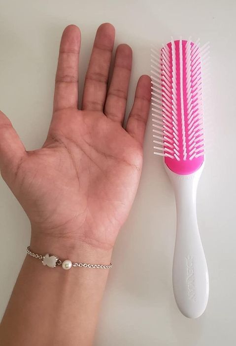 A reviewer places their hand beside a white brush on a table.