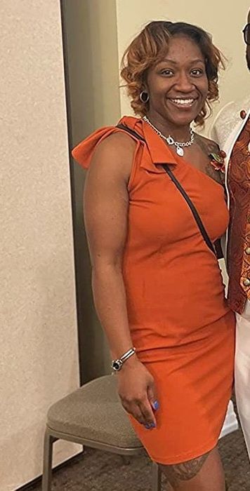 A reviewer showcases a bold orange-red dress, adding a vibrant touch to her outfit.