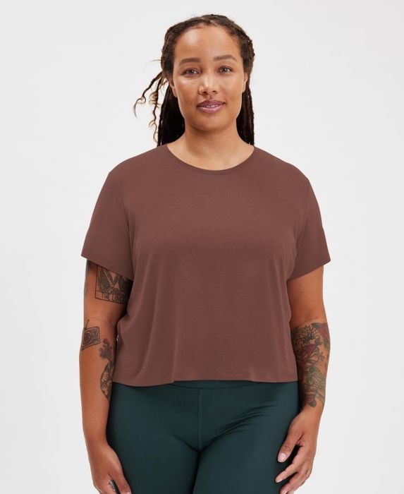 The model is showcasing a brown cropped tee paired with dark green leggings.