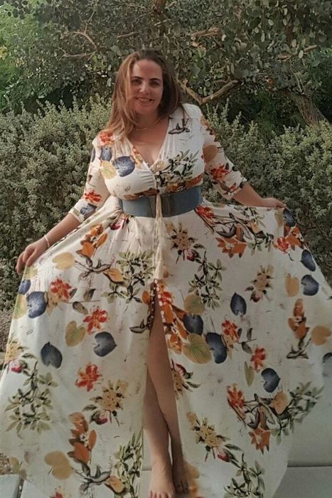 A reviewer modeling a long white floral dress with a slit