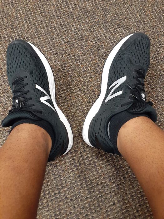 A reviewer showcases the black sneakers featuring a white 