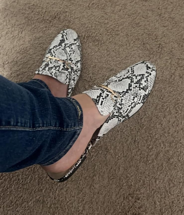person wearing snakeskin-patterned loafer mules paired with jeans