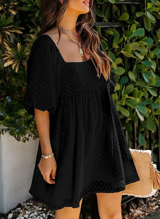 A model wearing a black dress with three-quarter length sleeves.