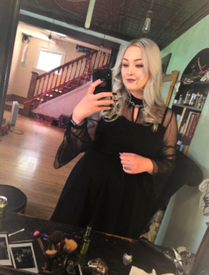 A reviewer is seen in a black dress with elegant mesh bell sleeves.