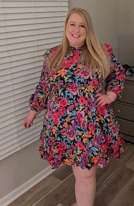 A reviewer in a vibrant multi-colored dress showcases her style.