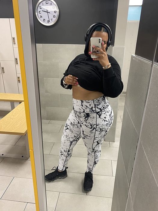 The reviewer is dressed in white leggings featuring a black marbled design, paired with black sneakers and a black hoodie.