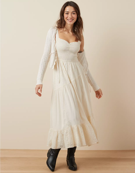 A woman wearing a flowing maxi dress with a sweetheart neckline and black boots