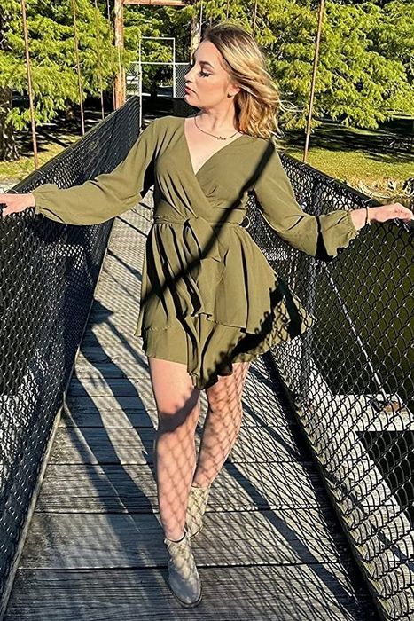 A reviewer striking a pose in a green dress on a bridge