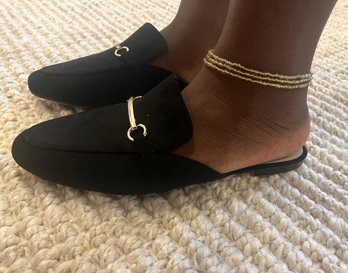 a reviewer showing off the same shoes in black with gold-tone horsebit accents