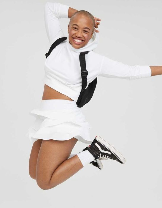 The model is wearing a crisp white hoodie and a matching white tennis skirt.