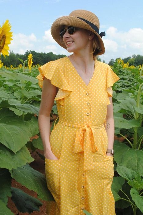 A reviewer sporting a wide-brimmed hat, sunglasses, and a yellow polka-dot dress