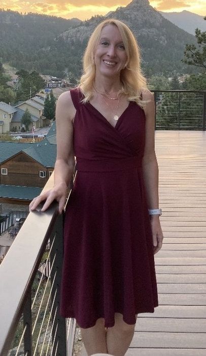 A reviewer sporting a sleeveless, knee-length V-neck dress