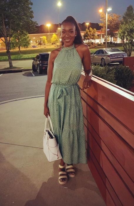 A reviewer showcasing the green spotted version of the dress, flaunting its flattering design