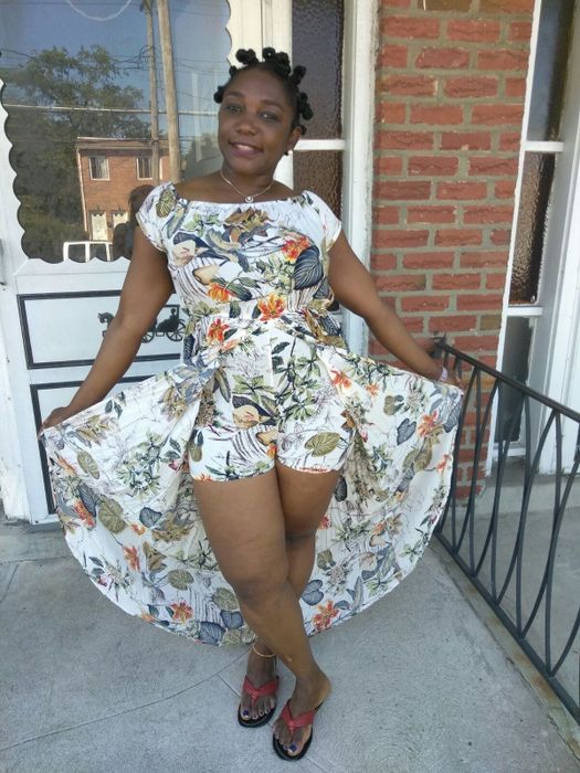 A reviewer wearing a white, green, and orange floral dress shares their thoughts.
