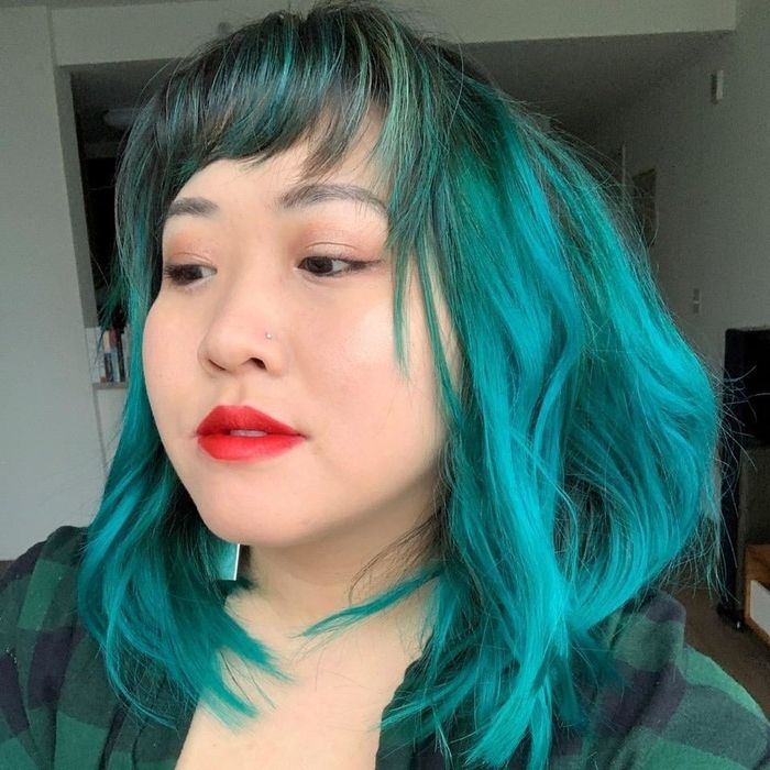 A reviewer showcasing their bright teal shoulder-length hair.