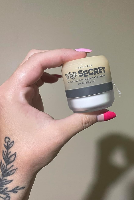A reviewer holding a small jar of the powder shampoo