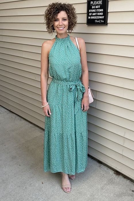A reviewer showcasing the dress in a green design with white polka dots