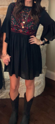 A reviewer showcasing the black dress, complemented by black cowboy boots.