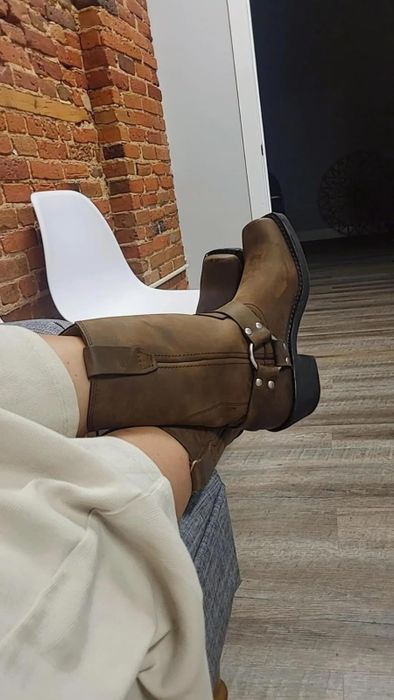 A reviewer is donning a pair of rugged harness boots.
