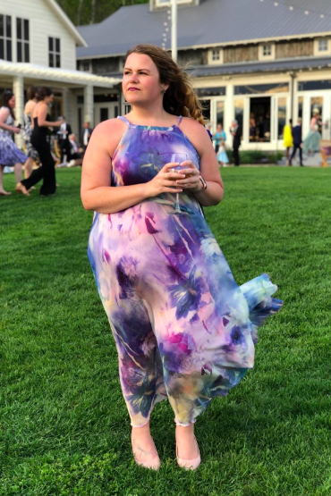 A reviewer dons the sleeveless dress featuring a bold abstract purple design