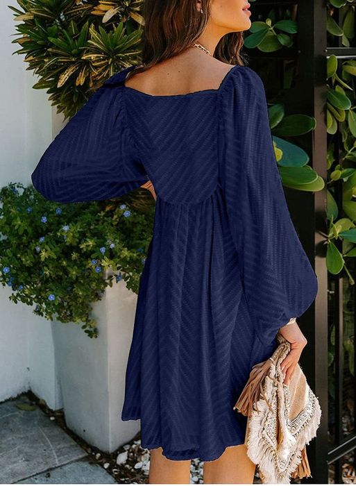 A model in a navy blue dress with long sleeves.