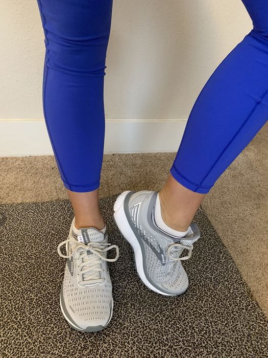 A reviewer demonstrates the gray sneakers with matching laces, crafted with breathable mesh for added comfort and ventilation.