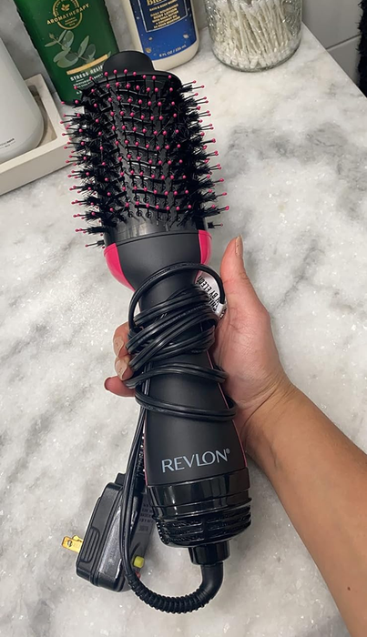 A hair dryer held in a reviewer's hand.