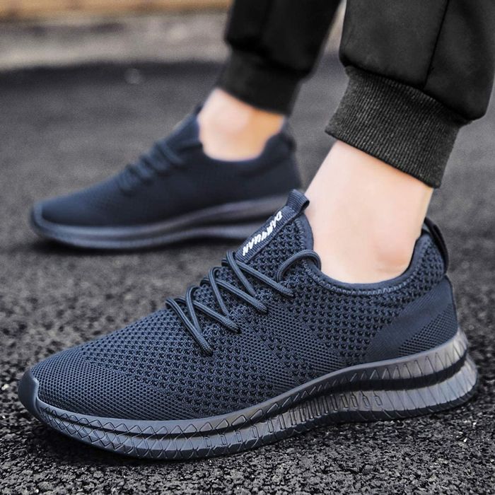 These black slip-on sneakers feature braided laces and a textured sole that thickens towards the heel for added support.
