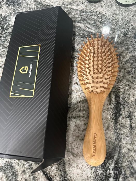 Wooden hairbrush with packaging featuring the brand logo