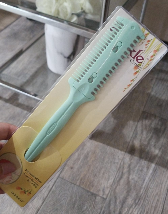 A reviewer holds up a blue cutting tool with sharp-edged combs for easy trimming.