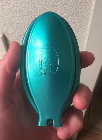 The same reviewer's teal brush folded for compact storage