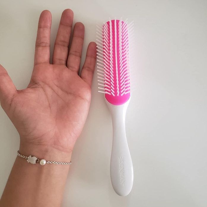 A reviewer’s hand placed next to a white brush on a table