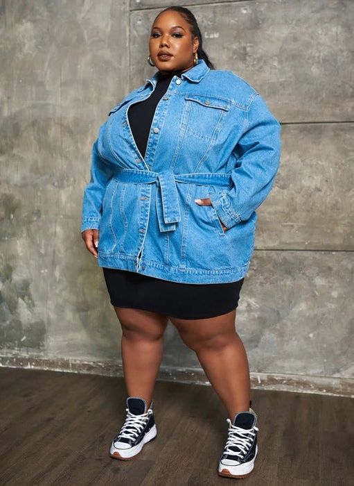 A model rocking the denim belted shacket, tied at the waist, paired with shorts and sneakers.