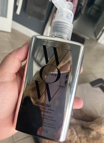 The reviewer holding the metallic bottle of the product.