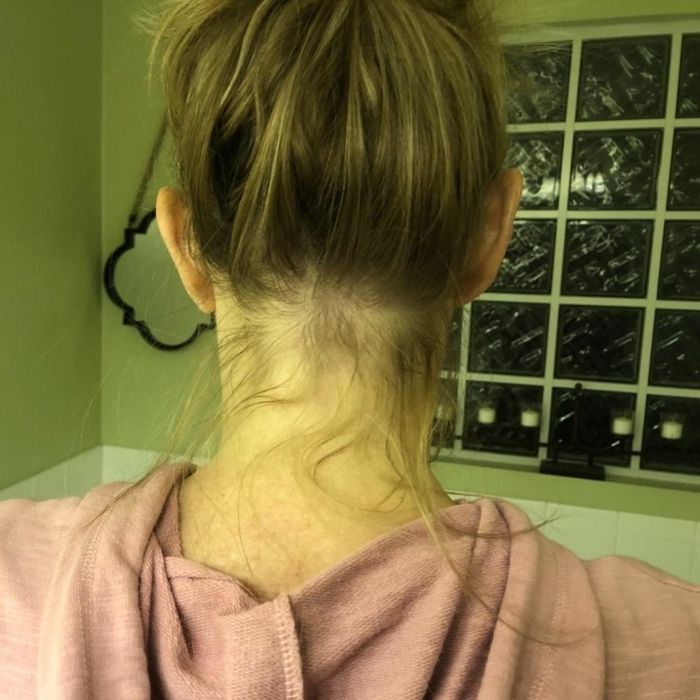 A reviewer showing her messy bun with flyaways peeking out from the back.