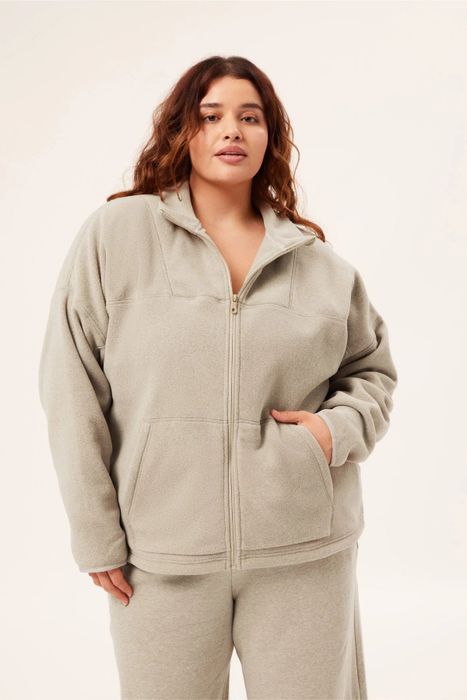 A model styling the full zip fleece jacket in a soft, light beige shade.