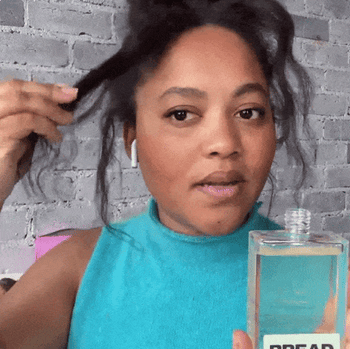 A gif showing a model applying hair oil to their curls