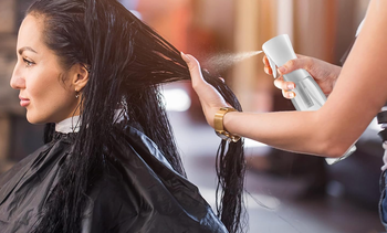 A model uses a water mister to refresh another model's hair.